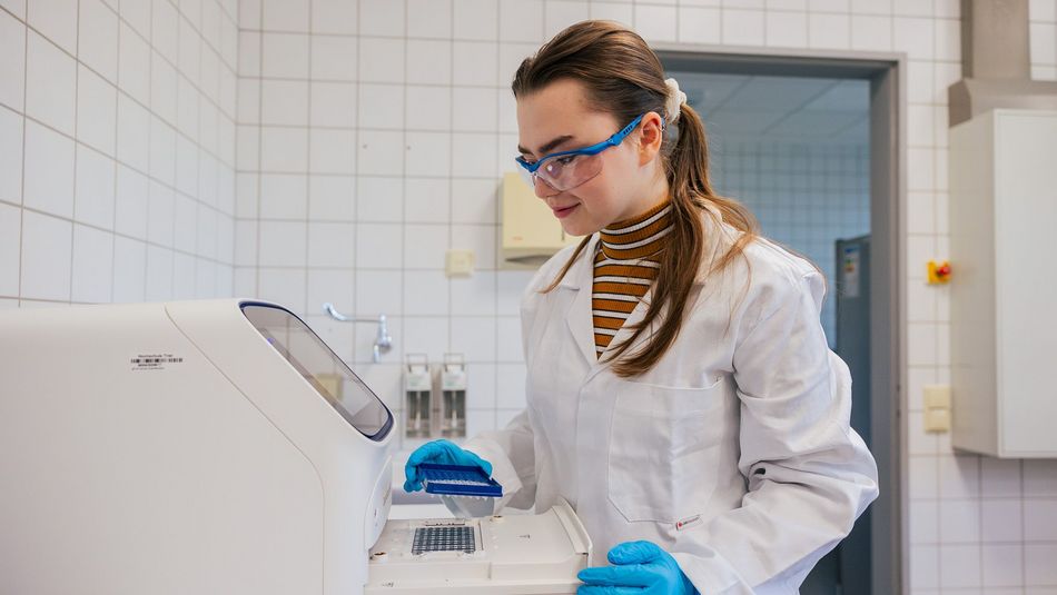 Studierende steht im Biologie-Labor der Hoschule Trier an der PCR und setzt eine Well-Platte ein