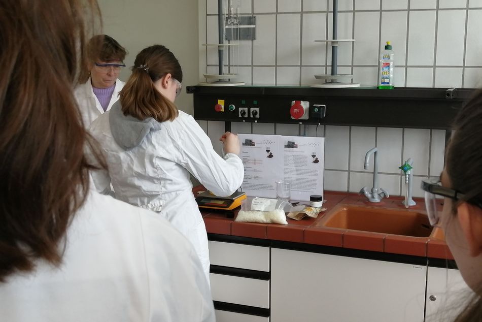Schülerinnen stehen im Labor und nehmen an einem Workshop teil und stellen eine Hautcreme her.