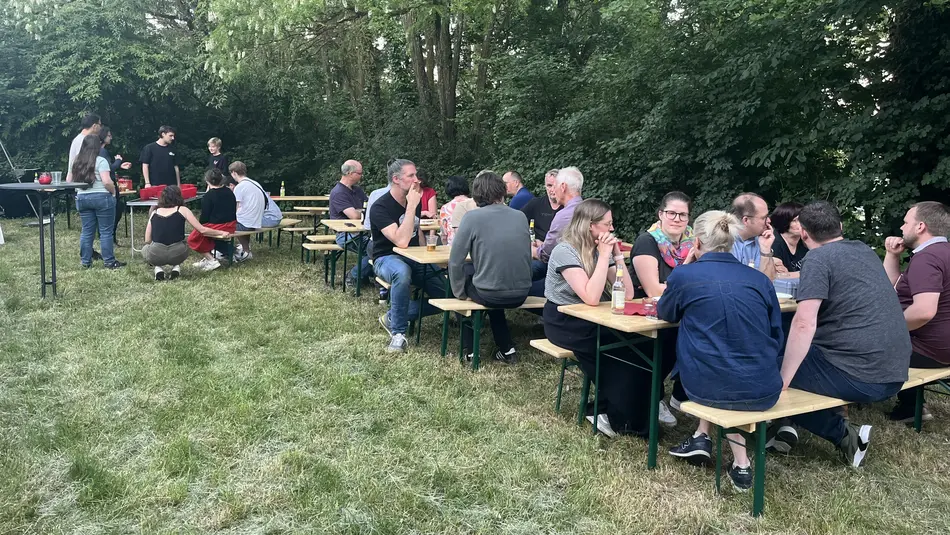 Mitarbeiter*innen und Professoren*innen des Fachbereichs Bauen+Leben sitzen draußen auf Bierbänken Hochschule Trier