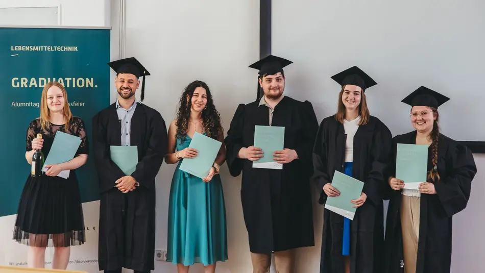 Absolvierende des Bachelor Lebensmitteltechnologie stehen in einer Reihe mit ihren Urkunden und Talaren zu einem Gruppenfoto