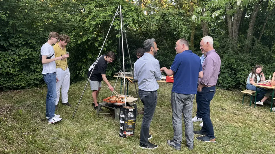 Mitarbeiter*innen und Professoren*innen des Fachbereichs Bauen+Leben stehen um den Grill Hochschule Trier