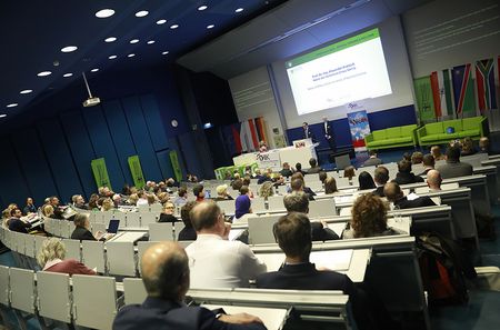 Blick in einen Hörsaal während der offiziellen Eröffnung des DHIK Forums 2026 mit Publikum und Rednern auf der Bühne.