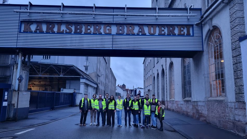 Studierende in Werkswesten vor dem Eingang der Karlsberg-Brauerei